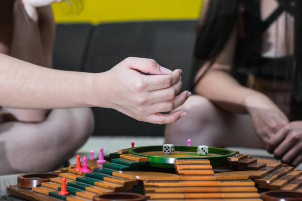 Close-up of a girl's hand moving a game piece during a fun and interactive girls weekend game night with friends.